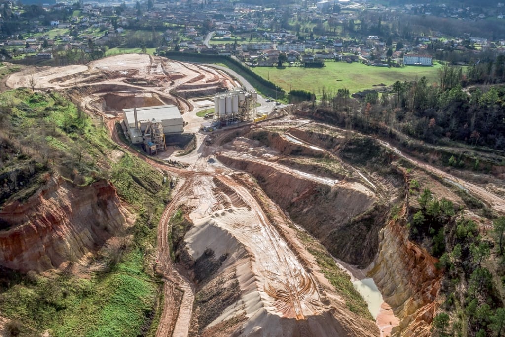 Panorama du gisement d’argile sableuse kaolinique de Fumel (Lot-et-Garonne). Au premier plan et au centre, un stock de sable 100/500 µm issu de l’opération de sélection granulométrique de l’entrant (refus). En haut, l’argile sableuse kaolinique mélangée, qui constitue le brut d’entrée. [©Argeco Développement]