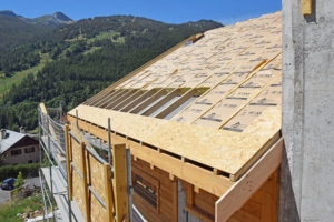 De l’intérieur vers l’extérieur, un sous-plafond en mélèze est posé sur chevrons. Il est ensuite recouvert d’un pare-vapeur. S’en suit la mise en place de deux couches de chevrons croisés, qui intègrent un total de 28 cm de laine de verre. L’ensemble est enfin recouvert de panneaux jointifs en OSB, accueillant le film d’étanchéité. Un lattage, cloué sur les panneaux en OSB, permet la fixation des bardeaux en mélèze. [©Lombard et Vasina]