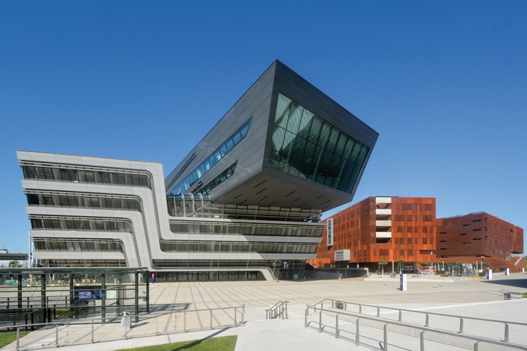 Les 42 000 m² de la bibliothèque de Vienne, conçue par Zaha Hadid, s'élèvent tel un bloc octogonal au sein du campus dédié aux sciences sociales et économiques. Les lignes droites à l'extérieur du bâtiment deviennent courbes à mesure que l'on entre dans la bibliothèque.  [©Pezi]