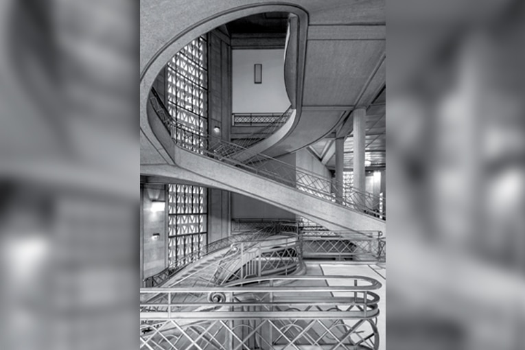 L’escalier semble ne reposer sur rien. Libre dans son volume, il est un élément vivant de l’architecture et paraît se tenir de lui-même du premier au troisième niveau, bien que des corbeaux ponctuels et des encastrements dans les planchers le lient aux poteaux de la façade sur cour et à la rotonde. [©ACPresse]