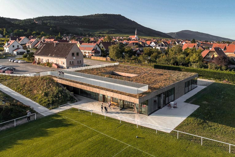 La Maison de la jeunesse et des sports est comme intégrée dans le terrain, qui l’enveloppe jusque sur la toiture-terrasse.  [©RHB Architectes]