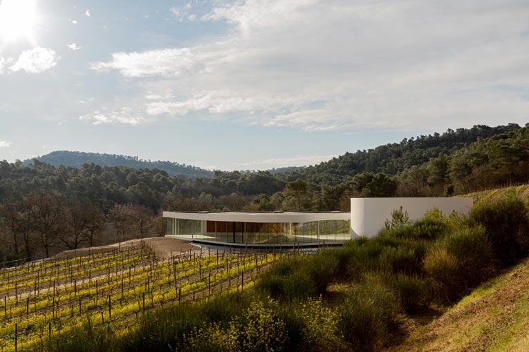 Construit au cœur du vignoble, le pavillon Oscar Niemeyer est un édifice en béton blanc tout en courbes, qui épouse le relief du coteau provençal où il est implanté. [©Château La Coste]