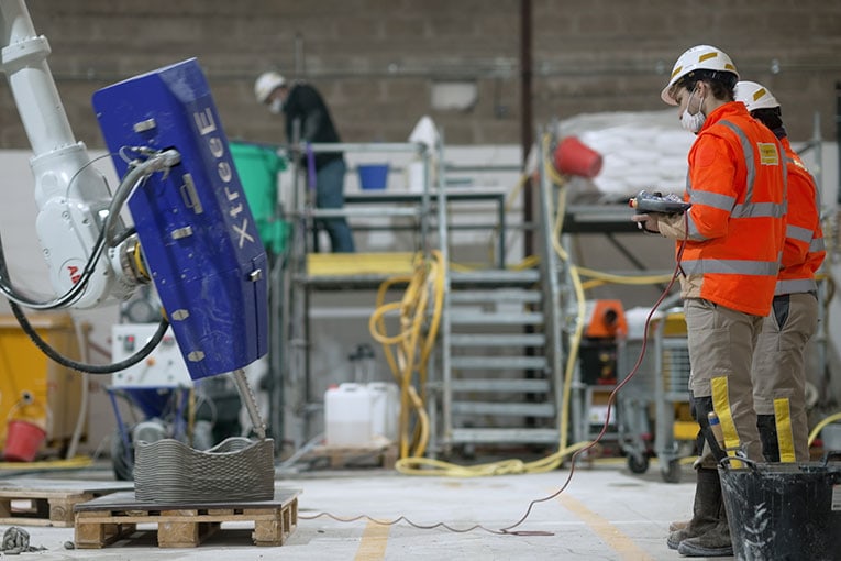 En France, le groupe de BTP Spie Batignolles a ouvert en 2021 son atelier de fabrication additive à Ollainville (91). Ce site héberge un bras robotisé six axes. Le tout est guidé par une technologie de modélisation brevetée par XtreeE. [©XtreeE]